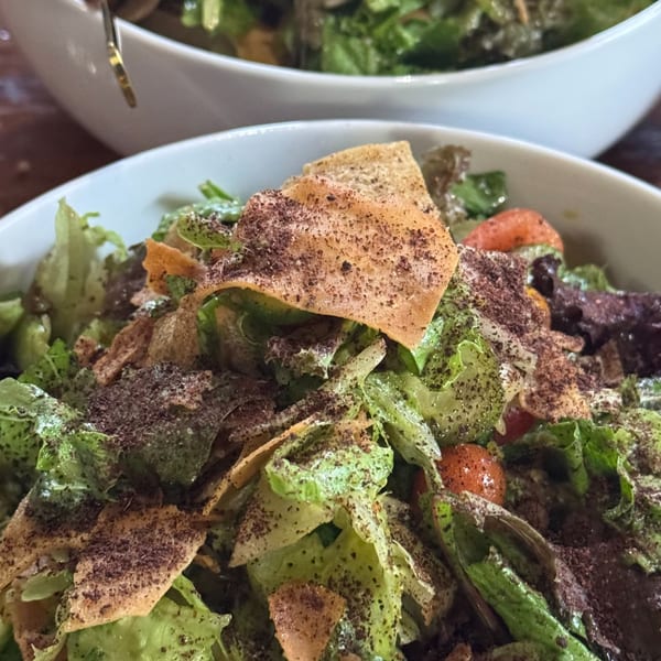Close-up of a fresh fattoush salad with lettuce, tomatoes, and crispy pita bread, sprinkled with sumac.