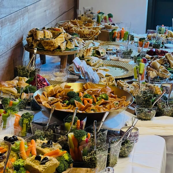 A lavish buffet spread with various appetizers, including wraps, chips, vegetables, and dips.