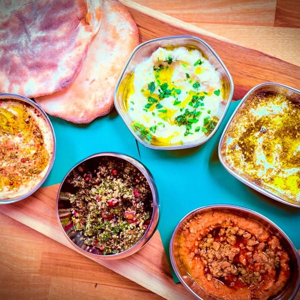 A vibrant spread of Middle Eastern dips and salads, including hummus, baba ghanoush, and tabbouleh, with pita bread.