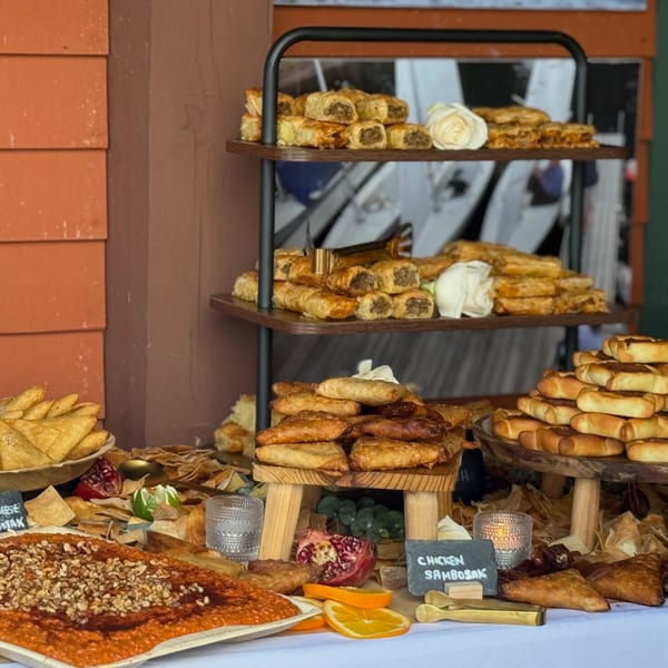 A buffet table laden with various Middle Eastern pastries, dips, and fresh fruit garnishes.